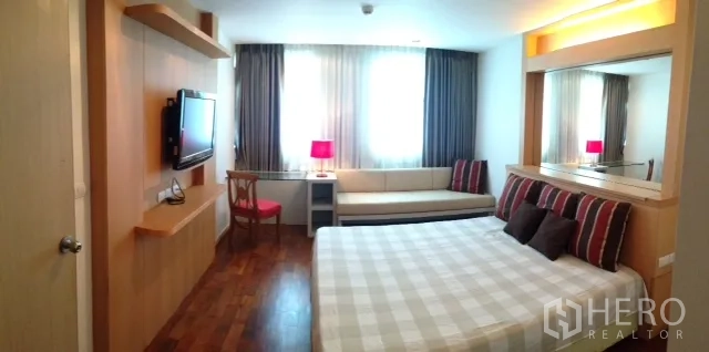 คอนโด ให้เช่าหรือขายในKhlong Toei, Bangkok - ห้องนอนสว่าง เตียงคิง ทีวีติดผนัง โซฟาริมหน้าต่าง พื้นไม้และหัวเตียงกระจก