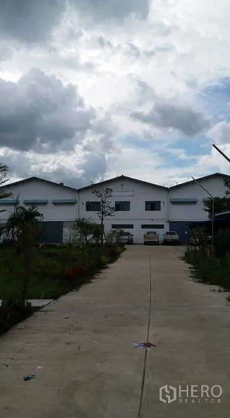 Warehouse for rent or sale in Nong Suea, Pathum Thani - Warehouse facade with loading doors and pickup trucks parked in front.