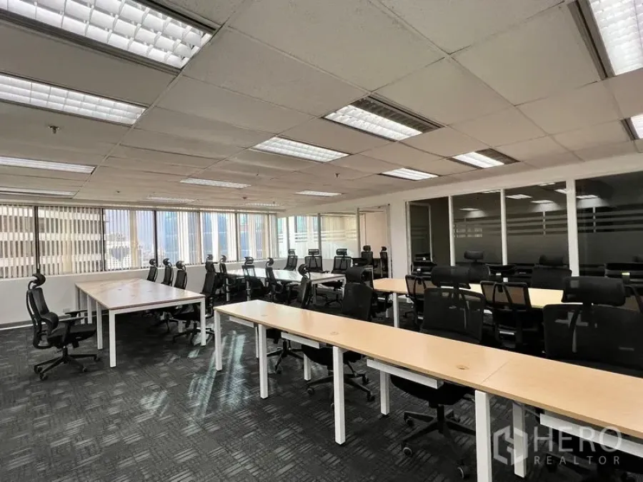 Office Space for rent in Khlong Toei, Bangkok - Spacious workspace with rows of desks and black task chairs, large windows, and glass-partitioned meeting rooms.