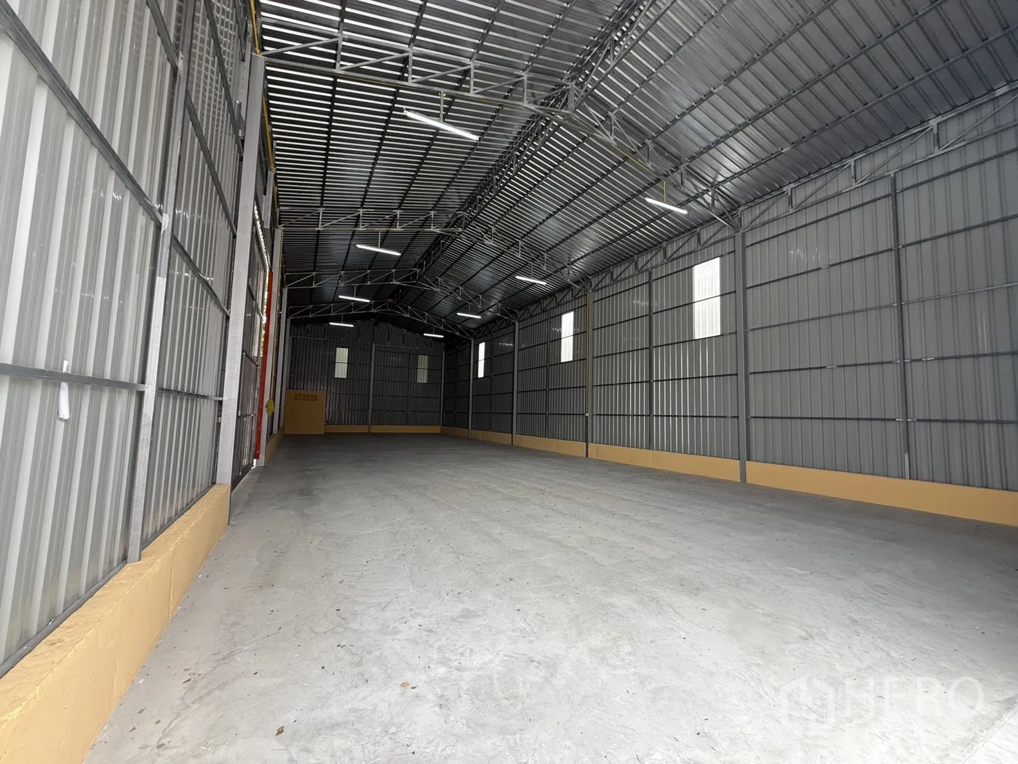 Warehouse for rent in Wang Thonglang, Bangkok - Long open warehouse bay with translucent panels and overhead lights.