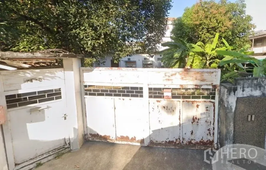 สำนักงานที่บ้าน ให้เช่าในChatuchak, Bangkok - ประตูรั้วเหล็กสีขาวมีรอยสนิม พร้อมต้นไม้ร่มรื่น ที่ทางเข้าบ้าน/โฮมออฟฟิศในเขตจตุจักร กรุงเทพฯ