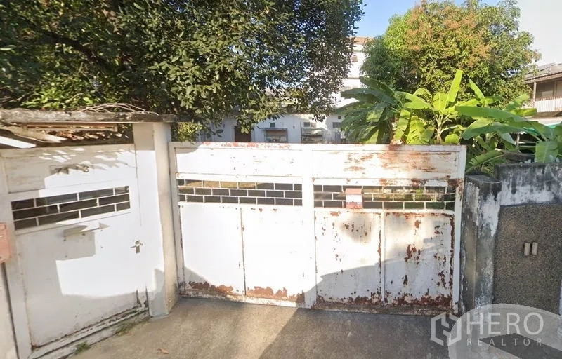 สำนักงานที่บ้าน ให้เช่าในChatuchak, Bangkok - ประตูรั้วเหล็กสีขาวมีรอยสนิม พร้อมต้นไม้ร่มรื่น ที่ทางเข้าบ้าน/โฮมออฟฟิศในเขตจตุจักร กรุงเทพฯ