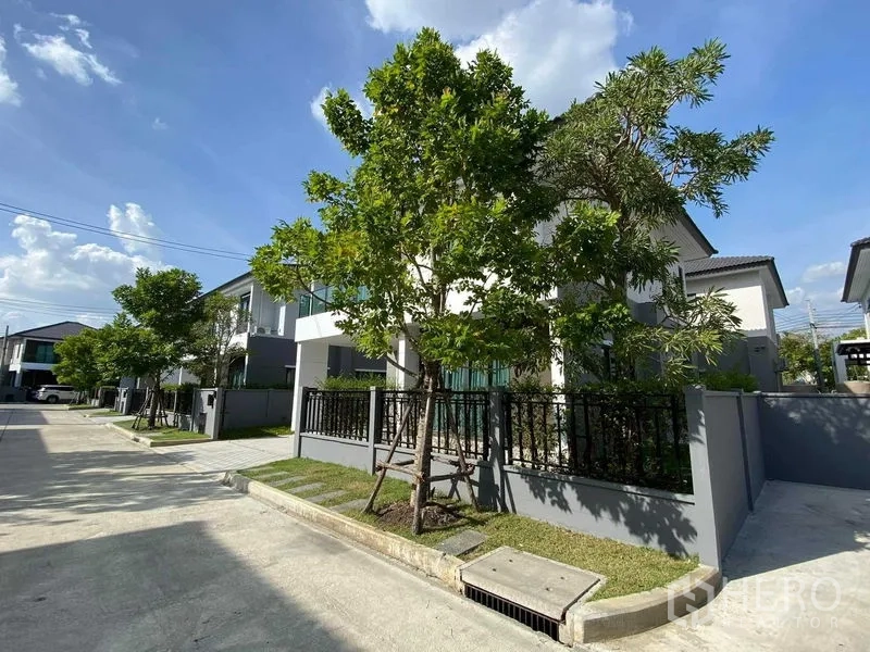 Detached House for rent in Don Mueang, Bangkok - Tree-lined residential street and corner view of a gated house.