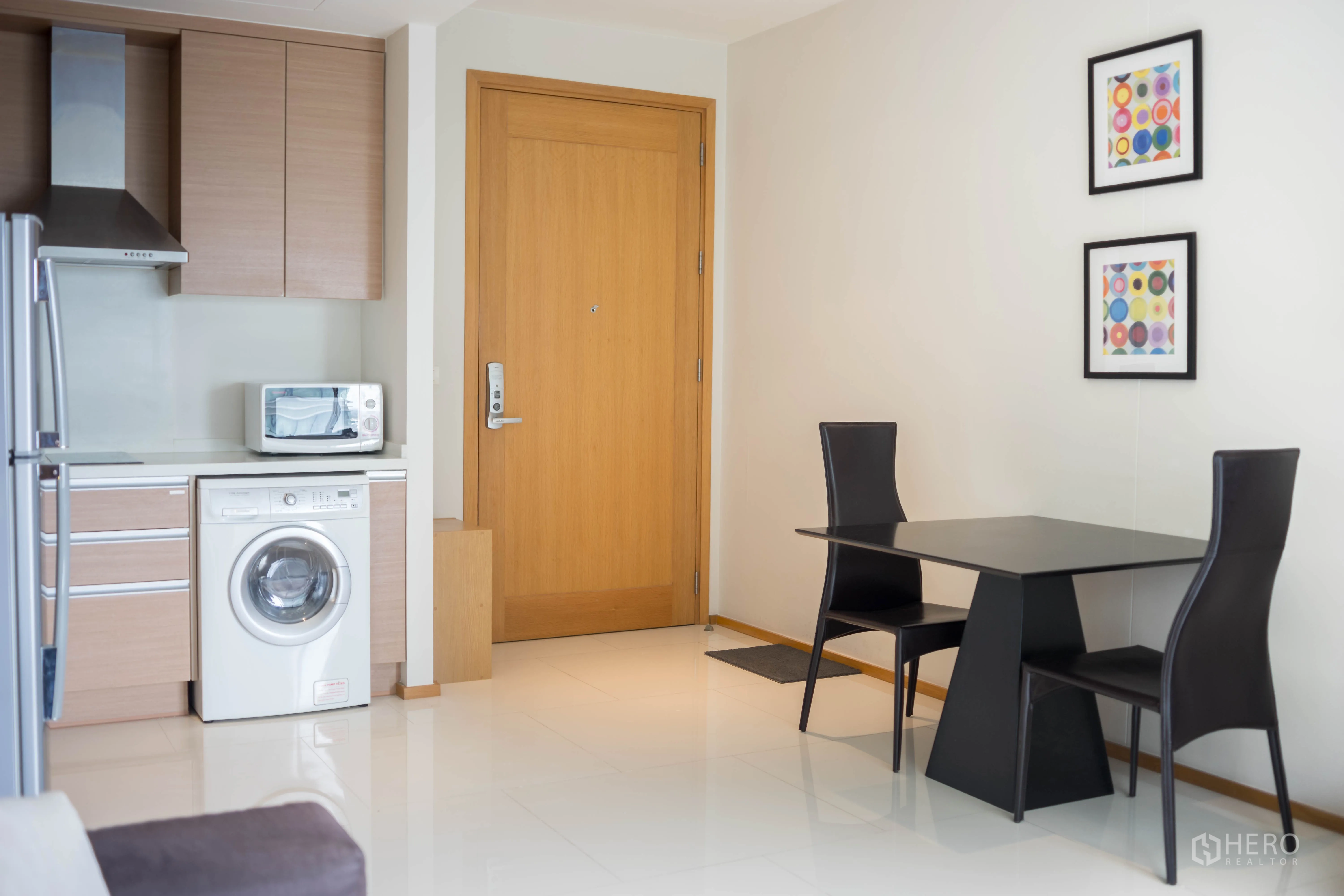 Condominium for rent or sale in Khlong Toei, Bangkok - Open-plan kitchenette with appliances, washing machine and a two-seat dining table.