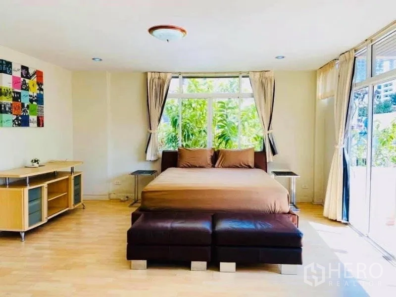 บ้าน ให้เช่าในWatthana, Bangkok - ห้องนอนกว้างเตียงคิงพร้อมออตโตมัน และหน้าต่างสูงเต็มบานรับวิวสวน