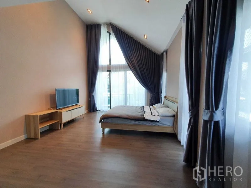 独立式住宅 出租在Khlong Luang, Pathum Thani - 主卧挑高天花，电视柜与大幅玻璃门，窗帘垂挂。