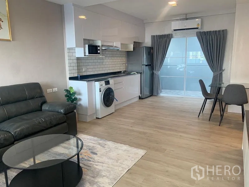 联排别墅 出租 - 明亮的一体化客餐厅与白色厨房，木地板和推拉玻璃门。