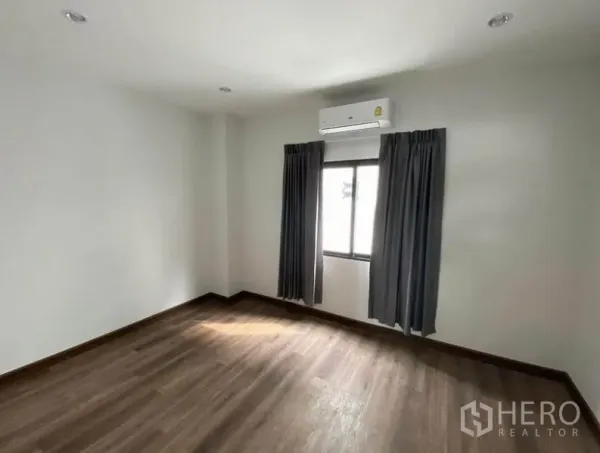 联排别墅 出租在Bang Na, Bangkok - 带空调的卧室，木地板、白色墙面与窗帘窗