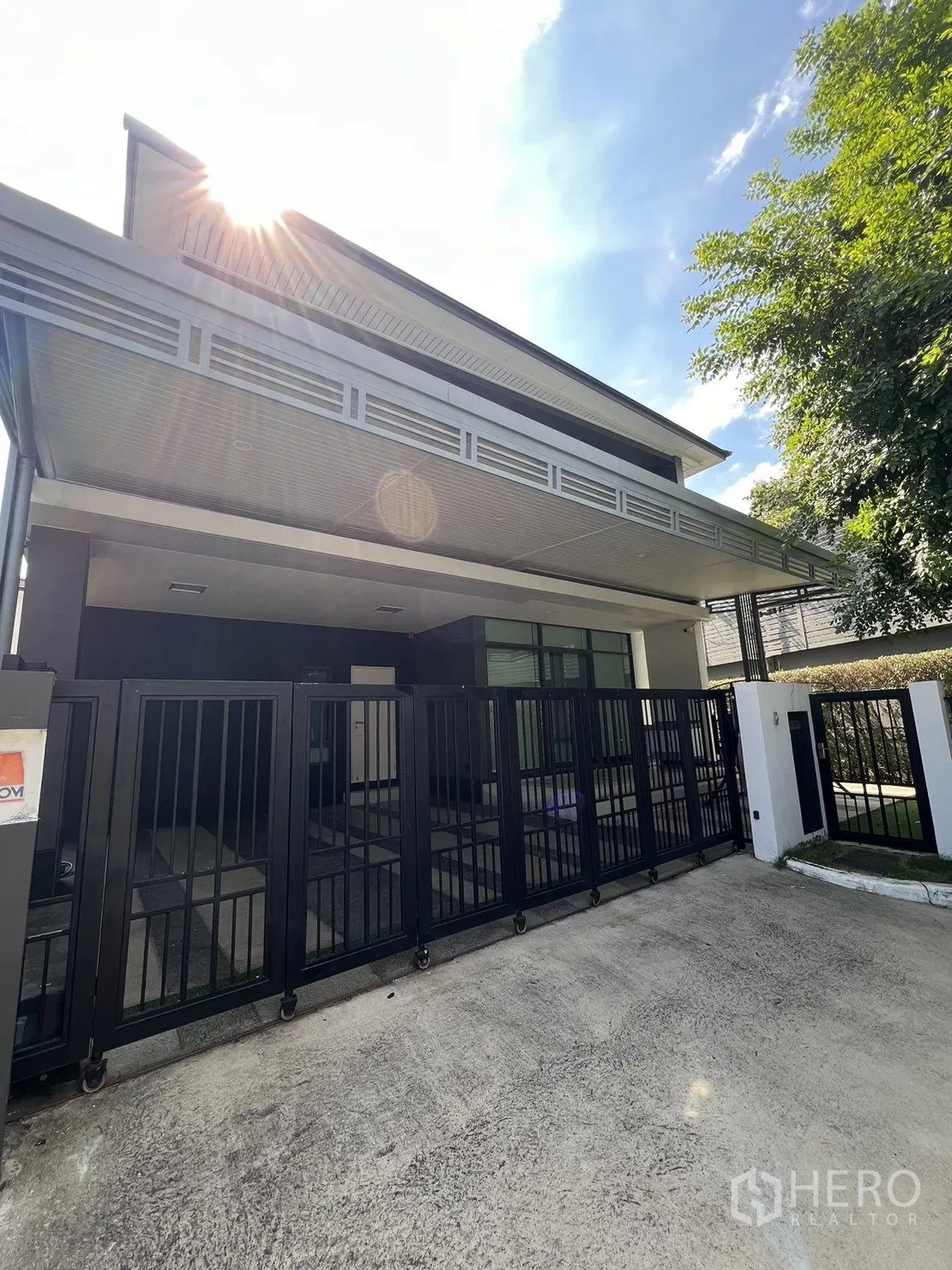 独立式住宅 出售在Bang Kapi, Bangkok - 现代两层转角别墅，黑色推拉大门，阳光洒落。