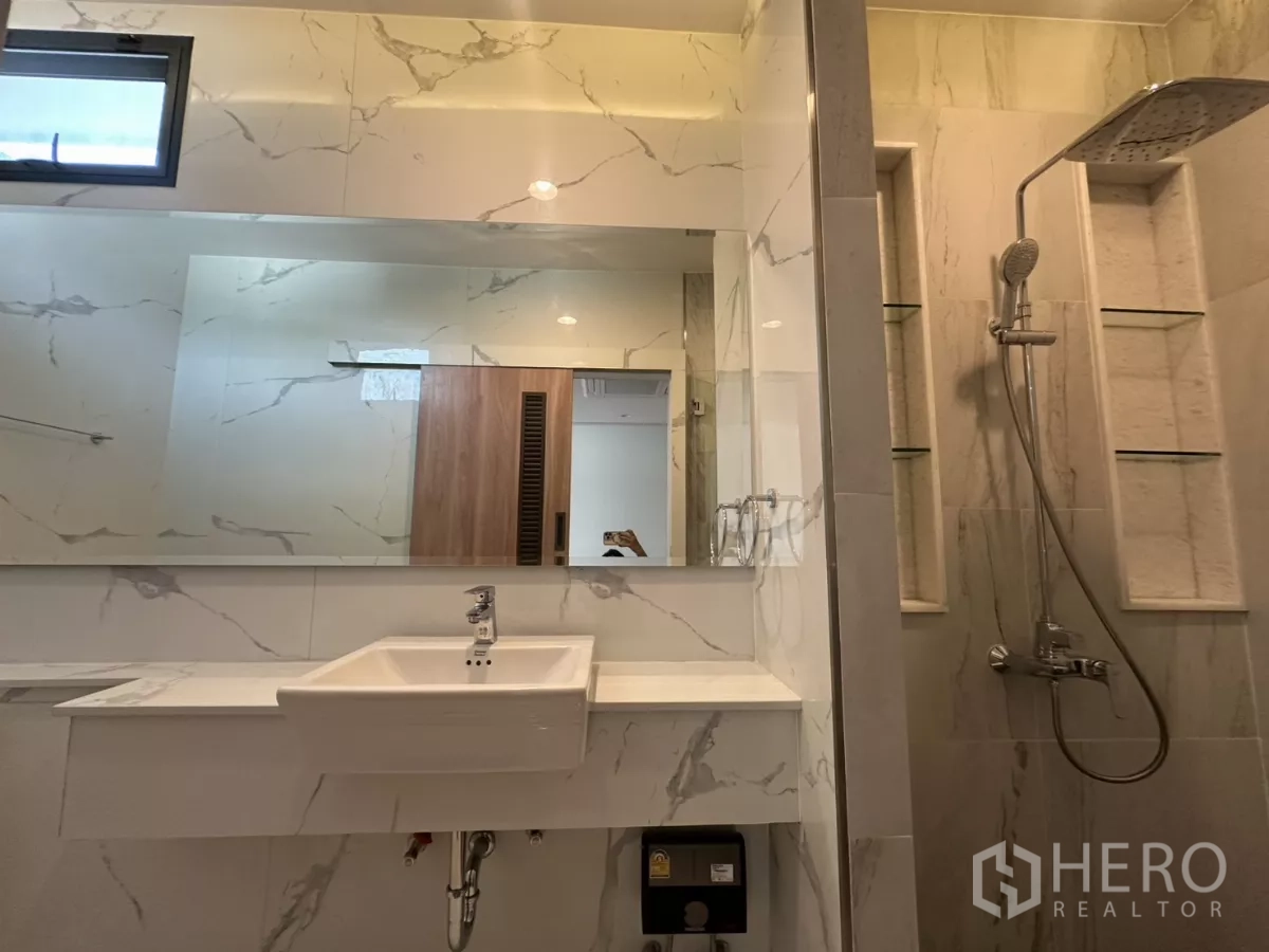 联排别墅 出租在Watthana, Bangkok - 浴室以大理石纹瓷砖、超长镜与雨淋花洒。