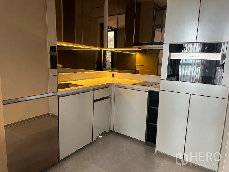 Condominium for rent - Sleek L-shaped kitchen with built-in oven, induction hob and under-cabinet lighting.