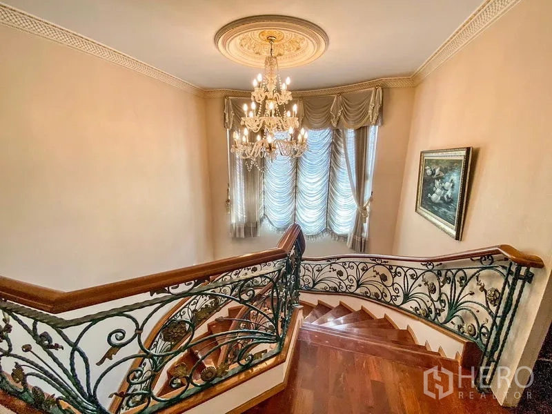 独立式住宅 出租或出售在Bang Khen, Bangkok - 二层楼梯平台，水晶吊灯、飘窗帘幔与花纹扶手。