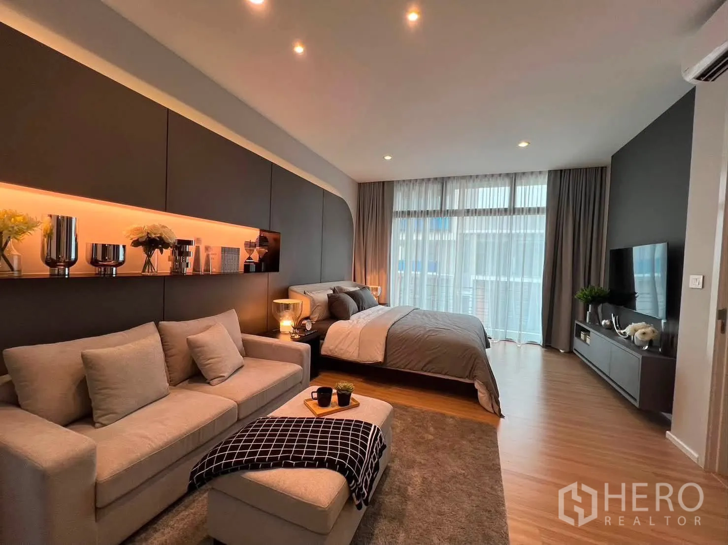 Townhouse for rent in Saphan Sung, Bangkok - Spacious master bedroom with sofa seating, TV unit, and floor-to-ceiling curtains.