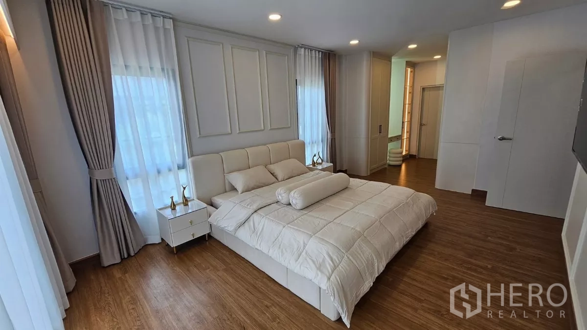 Detached House for rent or sale in Bang Phli, Samut Prakan - Spacious master bedroom with king bed, wood floors, multiple windows and entry to the ensuite and wardrobes.