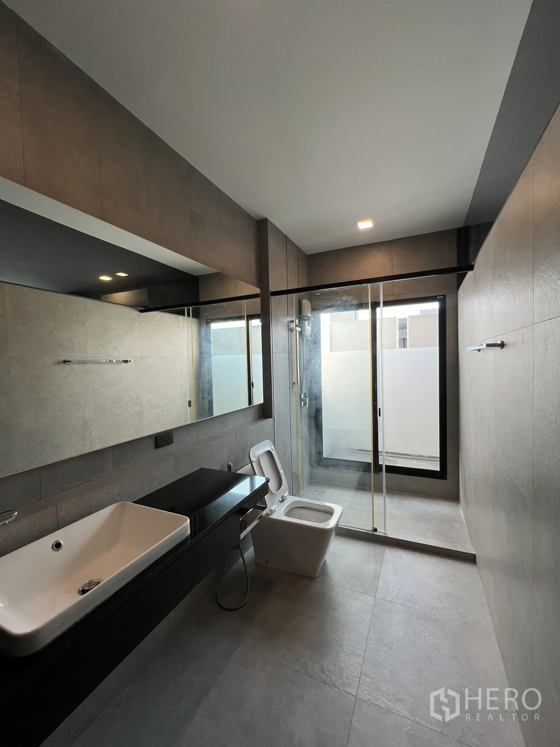 Detached House for rent in Bang Phli, Samut Prakan - Master bathroom with long vanity, toilet and glass shower enclosure.