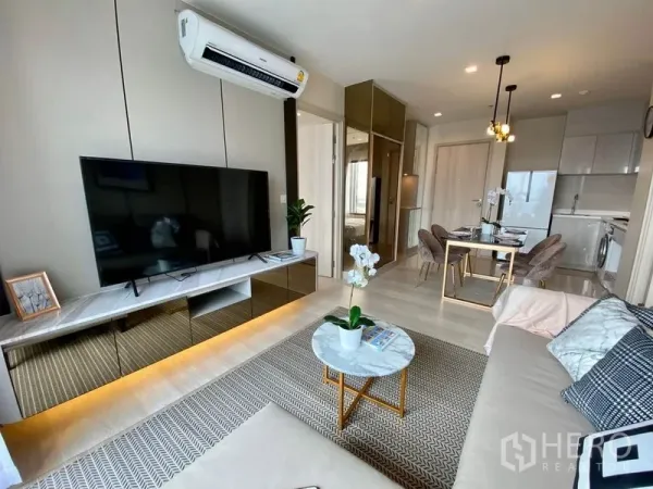 公寓 出租在Pathum Wan, Bangkok - 开放式起居区，电视与地毯，视线延伸至餐区和紧凑厨房。