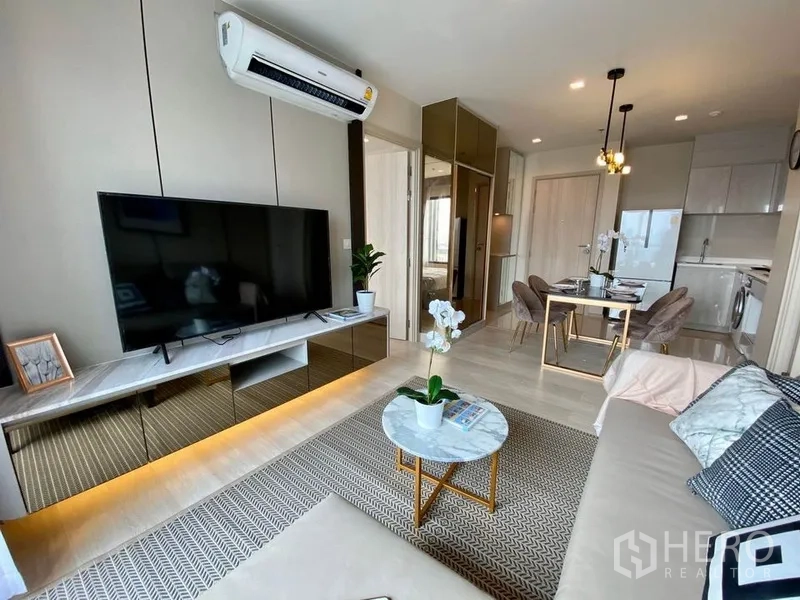 公寓 出租在Pathum Wan, Bangkok - 开放式起居区，电视与地毯，视线延伸至餐区和紧凑厨房。