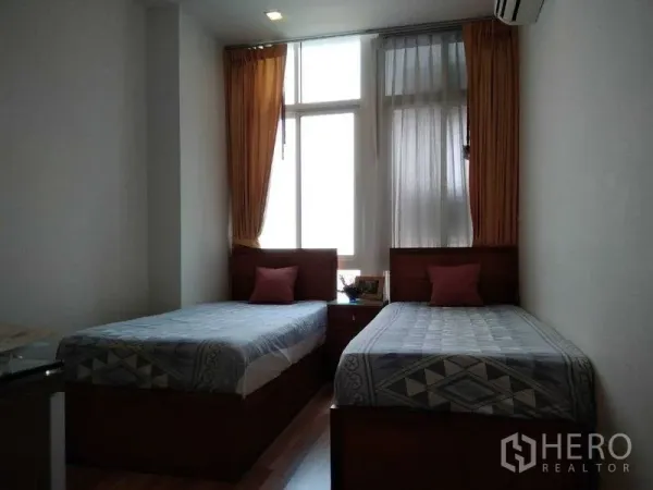 Condominium for rent in Watthana, Bangkok - Second bedroom with two single beds, tall window, and air conditioning.