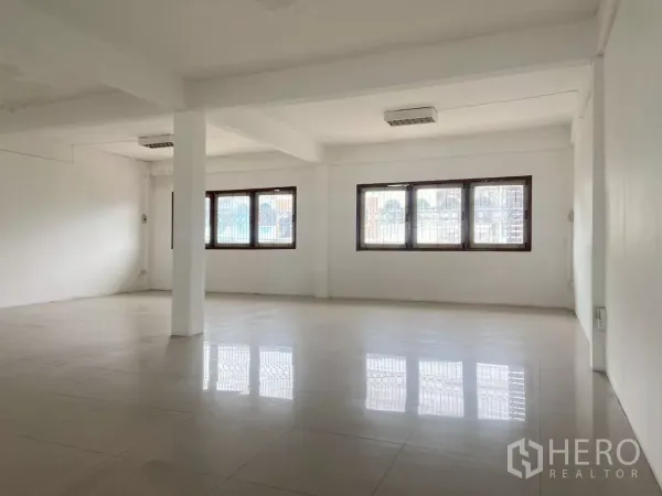 Shophouse for rent in Prawet, Bangkok - Large upper-floor room with tiled flooring and a row of windows, ideal for office use.