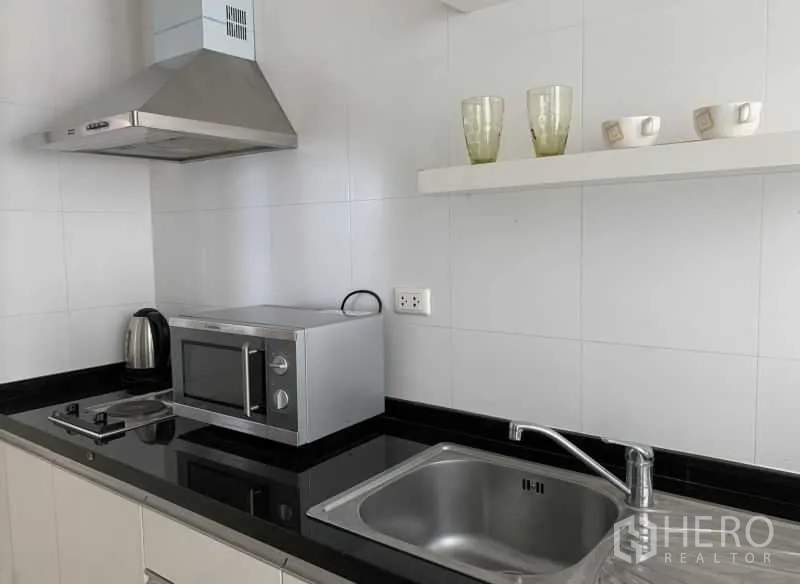 คอนโด ให้เช่าในKhlong Toei, Bangkok - ครัวยุโรปท็อปสีดำ มีอ่างล้างจาน ไมโครเวฟ เตา และเครื่องดูดควัน