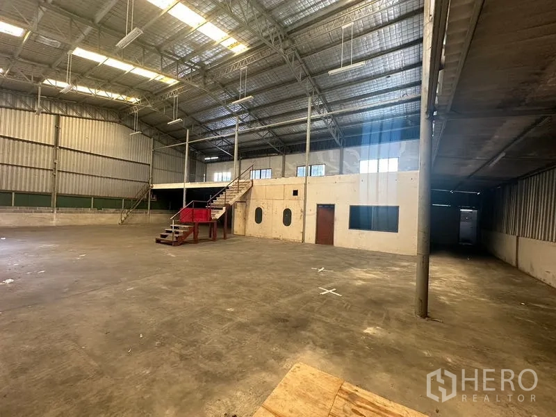 Warehouse for rent in Suan Luang, Bangkok - Open industrial floor with concrete slab, internal office block and mezzanine staircase.