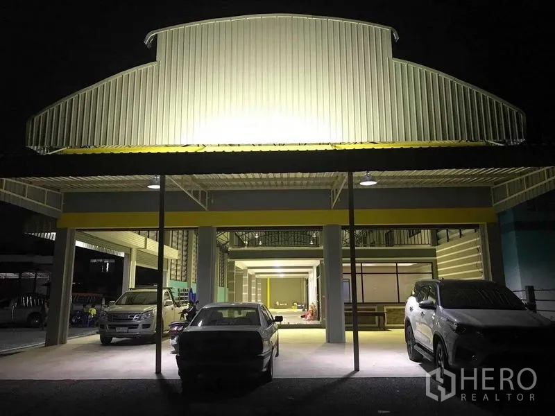 Warehouse for rent in Bang Pakong, Chachoengsao - Night view of the warehouse entrance canopy with illuminated parking bays and vehicles.