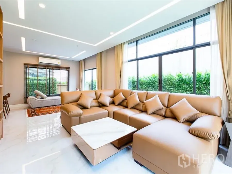 独立式住宅 出租或出售在Prawet, Bangkok - 开放式起居室，L形沙发、大理石地面与全高窗