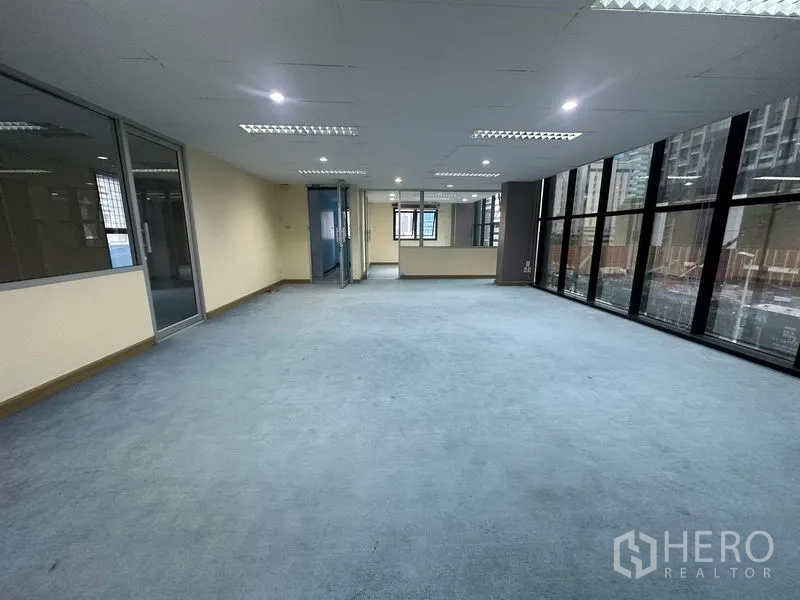 办公空间 出租在Bang Rak, Bangkok - 宽阔办公区，整排高窗与明亮的吊顶灯。