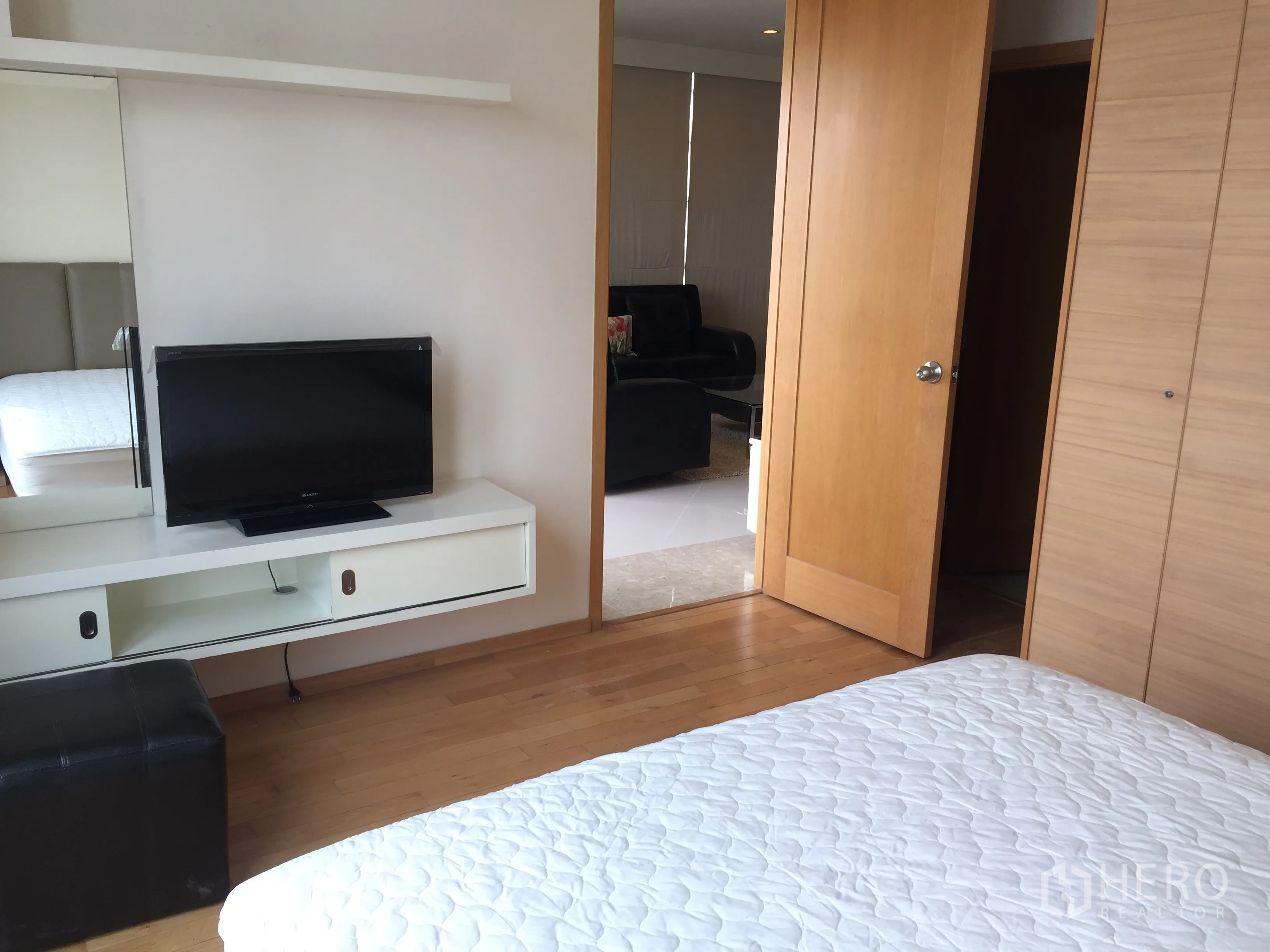 公寓 出租在Sathon, Bangkok - 卧室电视柜与木衣柜，可通往客厅的门厅视角。