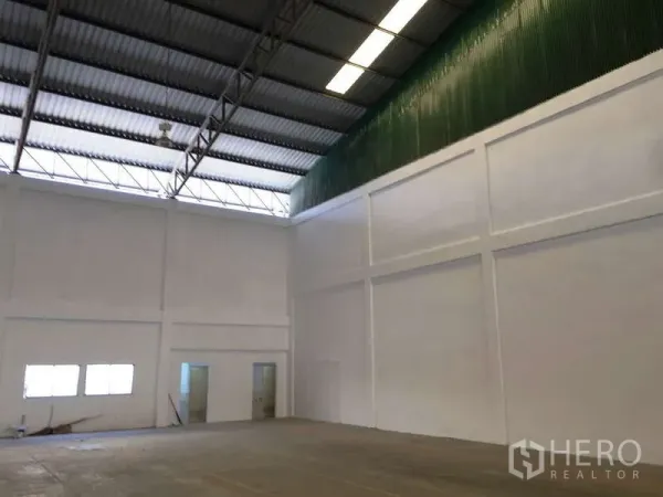 Factory for rent in Bang Bo, Samut Prakan - Interior corner with green ventilated wall and doors to office and restrooms.