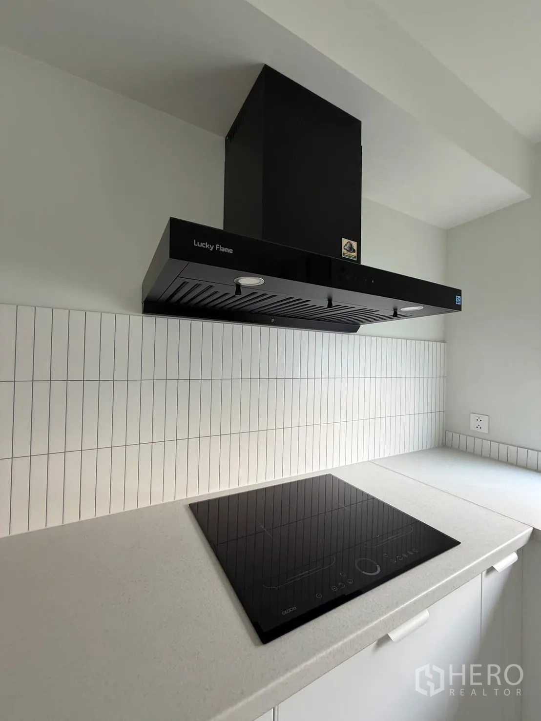 บ้าน ให้เช่าในBang Na, Bangkok - ภาพระยะใกล้เตาอินดักชันและเครื่องดูดควันสีดำ พื้นหลังกระเบื้องสีขาว