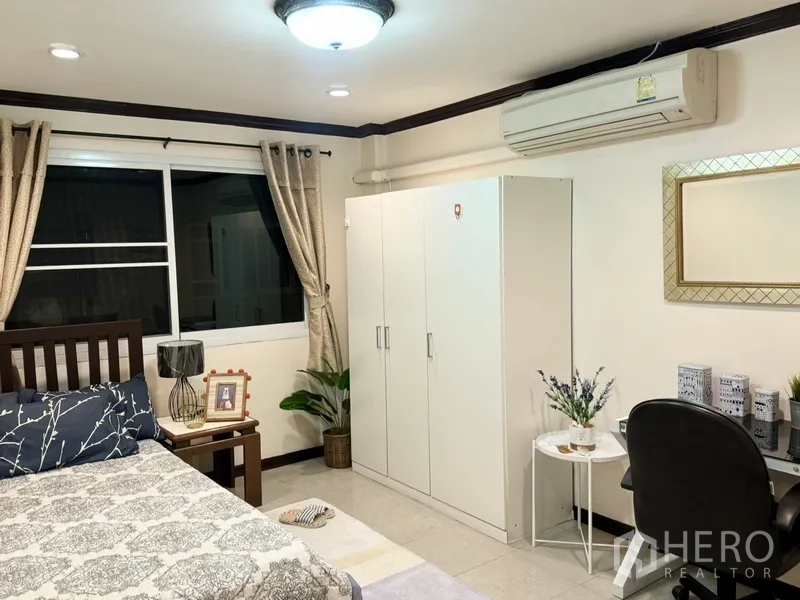 联排别墅 出租在Prawet, Bangkok - 空调卧室，书桌、白色衣柜与窗帘。