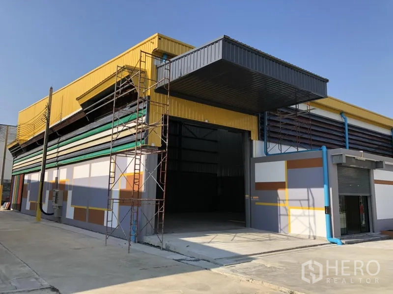 工厂 出租在Khlong Luang, Pathum Thani - 工厂单元转角视图，入口开启，正在进行收尾脚手架作业。