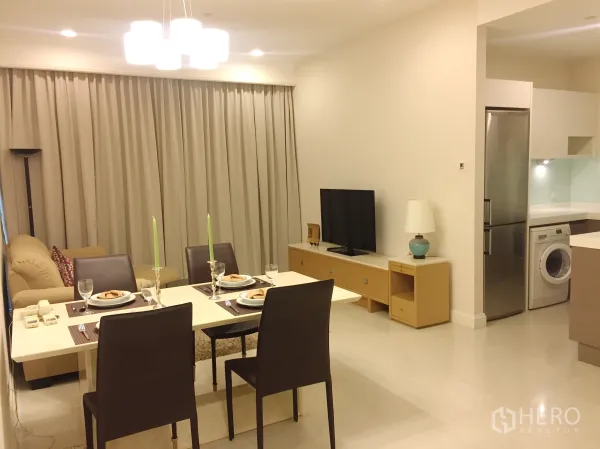Condominium for rent in Pathum Wan, Bangkok - Open-plan living and dining area with set table, sofa and TV, next to the kitchen.