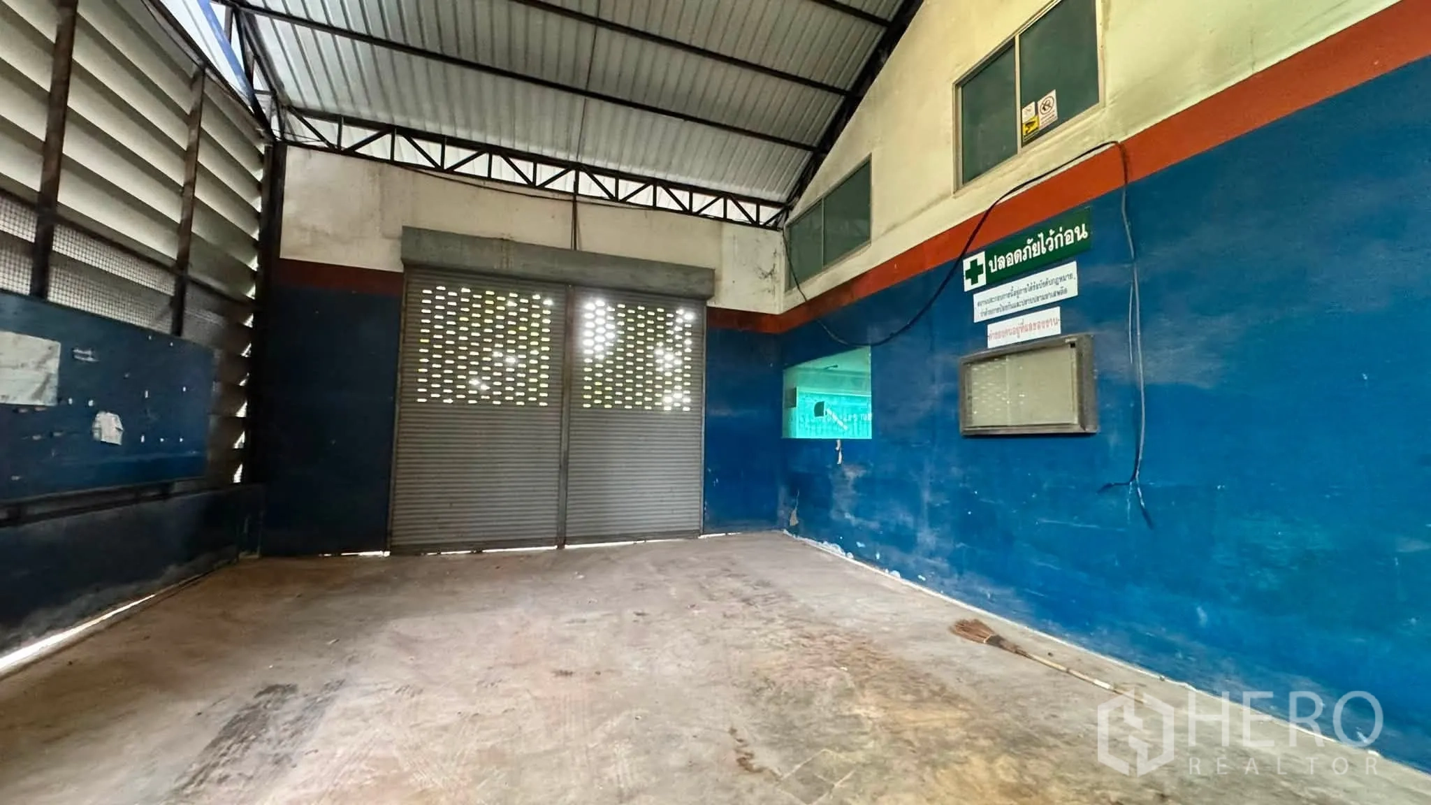 Warehouse for rent in Bang Khen, Bangkok - Loading area with metal roller shutter and ventilation panels inside the warehouse.