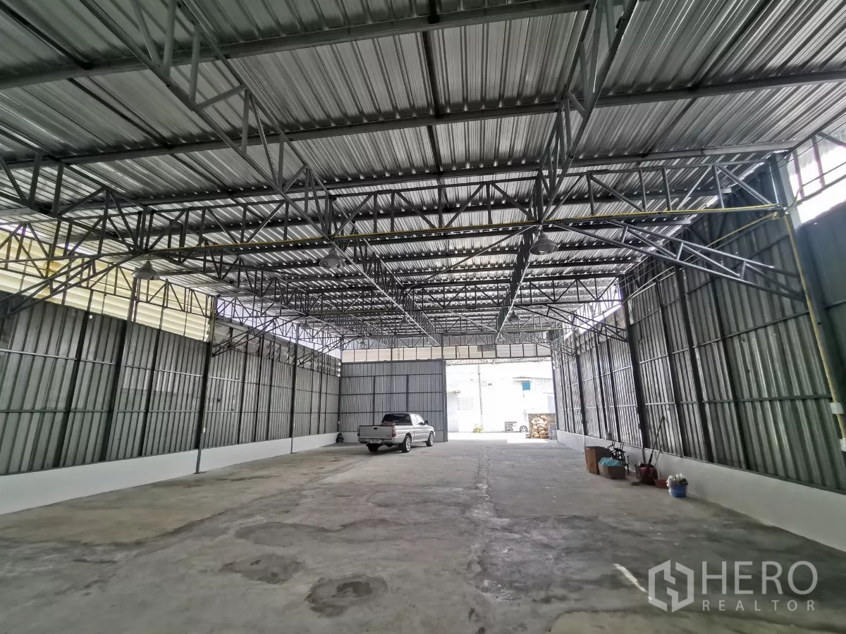 Warehouse for rent in Min Buri, Bangkok - Spacious warehouse interior showing high steel truss roof, concrete floor and truck access.