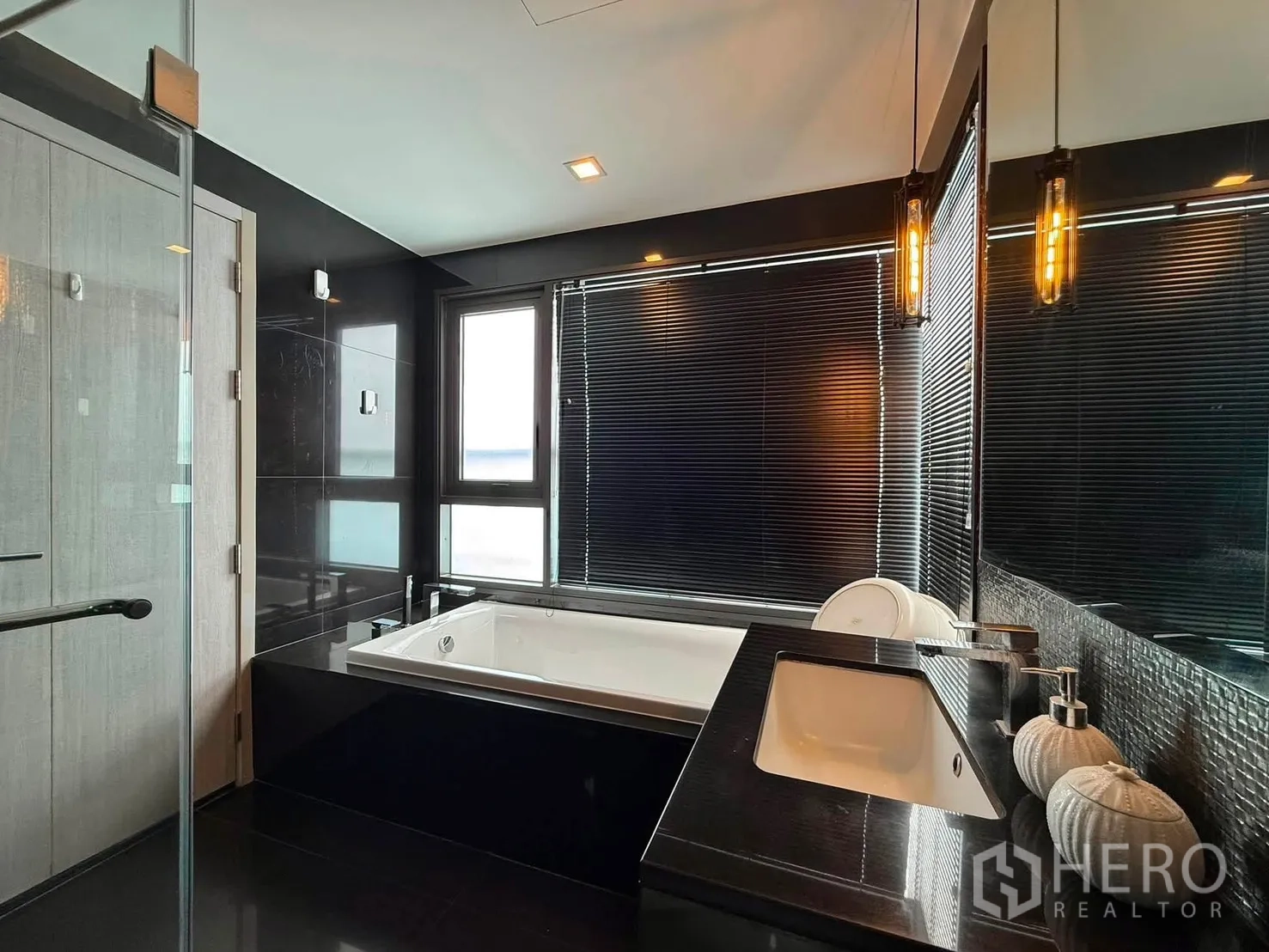 Condominium for rent in Khlong Toei, Bangkok - Luxury bathroom with soaking bathtub, window, and polished vanity.