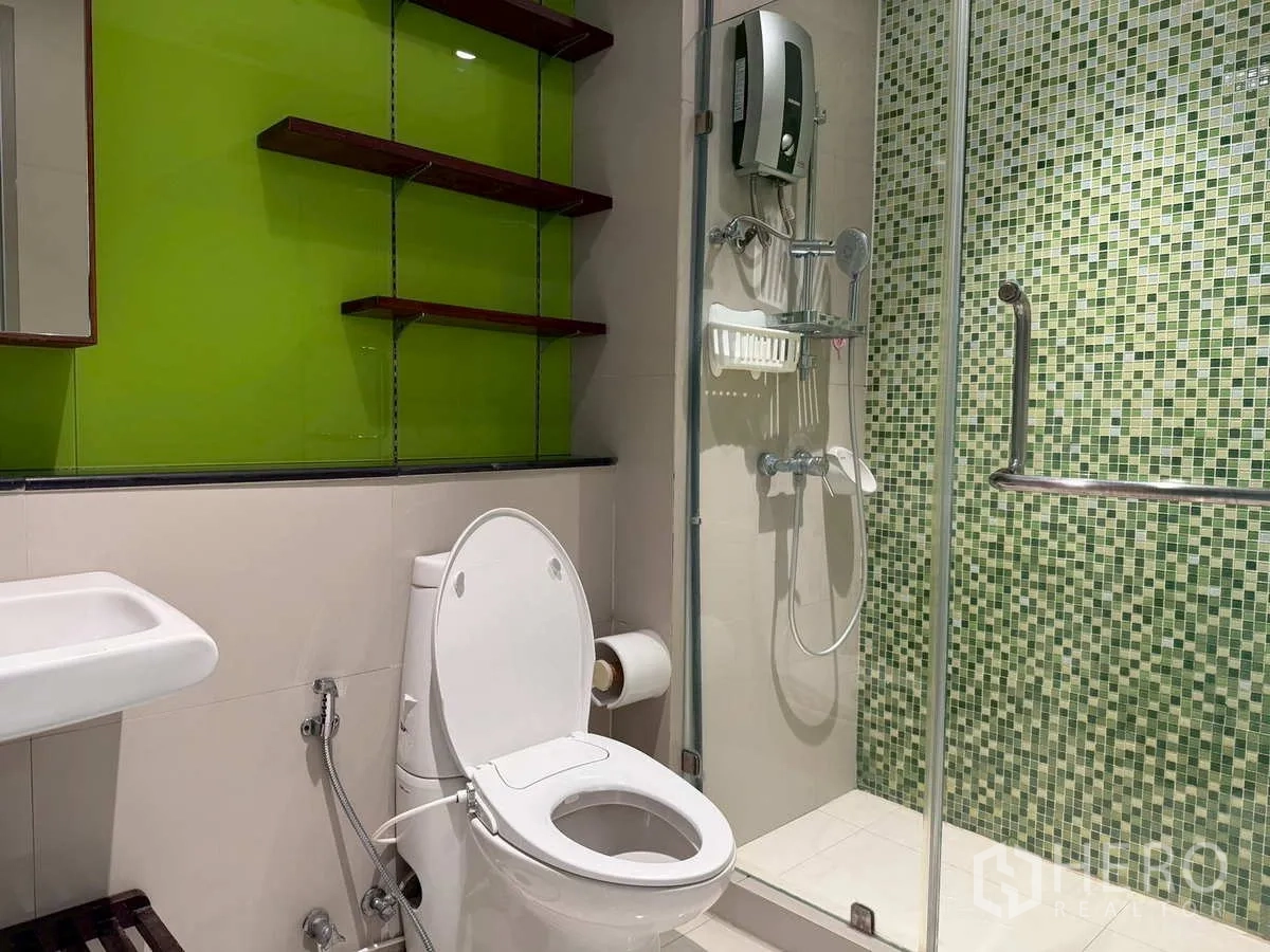 Condominium for rent or sale in Khlong Toei, Bangkok - Contemporary bathroom with glass shower and green mosaic wall.