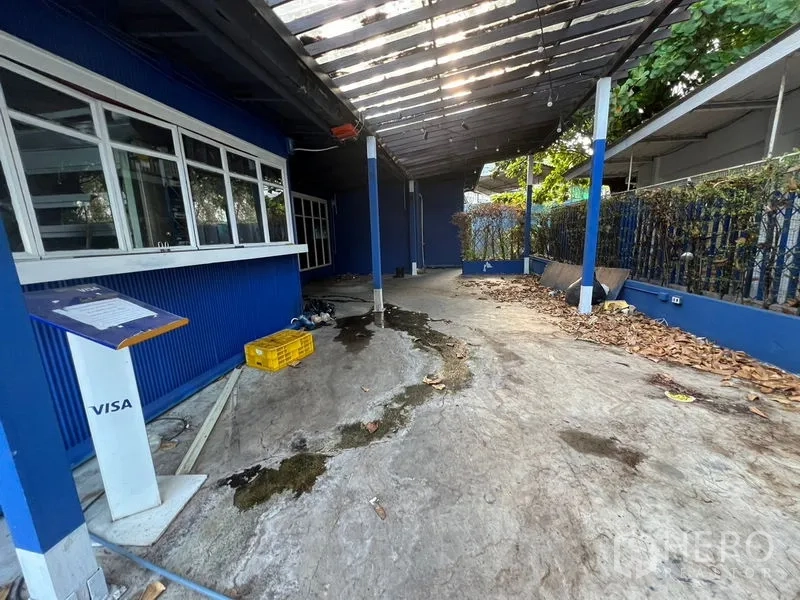 零售空间 出租在Watthana, Bangkok - 带顶棚的室外走道与服务窗口，蓝色外墙