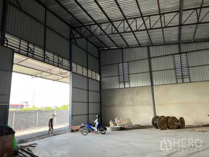 Warehouse for rent in Lam Luk Ka, Pathum Thani - Tall roller shutter entrance opening to a covered loading area, truck-friendly concrete floor.
