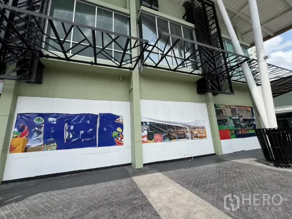 零售空间 出租 - 临街店面，宽幅遮挡海报与金属雨棚，上方为玻璃窗。