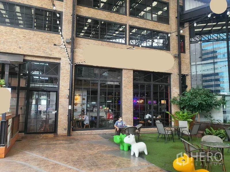 พื้นที่ขายปลีก ให้เช่าในKhlong Toei, Bangkok - ด้านหน้าอาคารอิฐโชว์แนว กระจกกรอบดำสูง มีลานนั่งด้านนอก ไฟประดับและต้นไม้ ในย่านพร้อมพงษ์