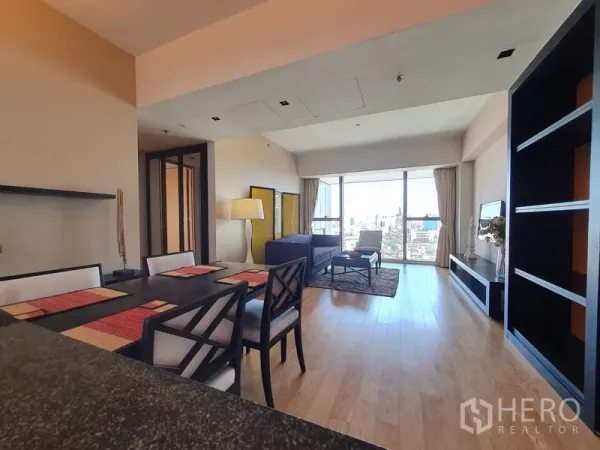 Condominium for rent in Sathon, Bangkok - Open-plan living and dining area with wood flooring and wide balcony glazing.