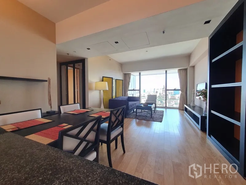 Condominium for rent in Sathon, Bangkok - Open-plan living and dining area with wood flooring and wide balcony glazing.