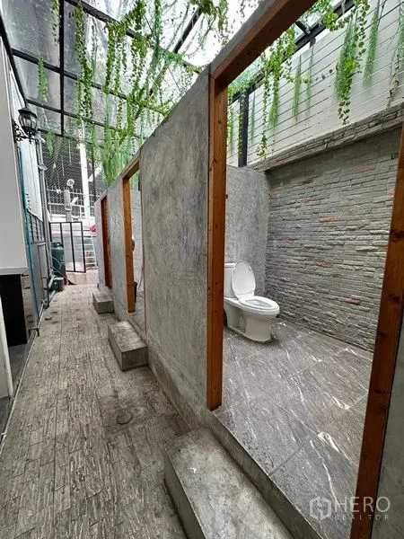 Retail Space for rent in Suan Luang, Bangkok - Restroom area with open-top stalls, stone-textured walls and overhead greenery beneath a clear roof.