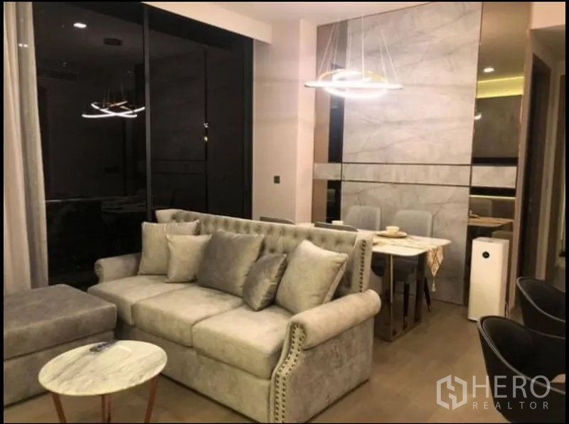 คอนโด ให้เช่าในWatthana, Bangkok - ห้องนั่งเล่นโทนเทาพร้อมโซฟาบุผ้า ผนังลายหินอ่อน และหน้าต่างสูงเต็มบาน