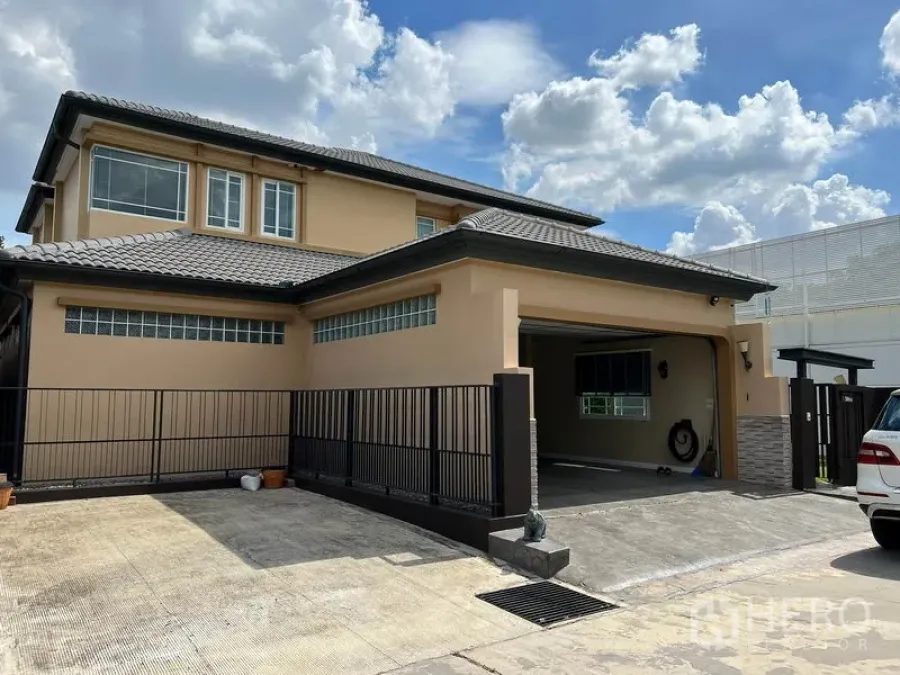 Detached House for rent in Bang Kapi, Bangkok - Two-story detached house with tiled roof, gated driveway and covered carport in Bang Kapi under blue sky.