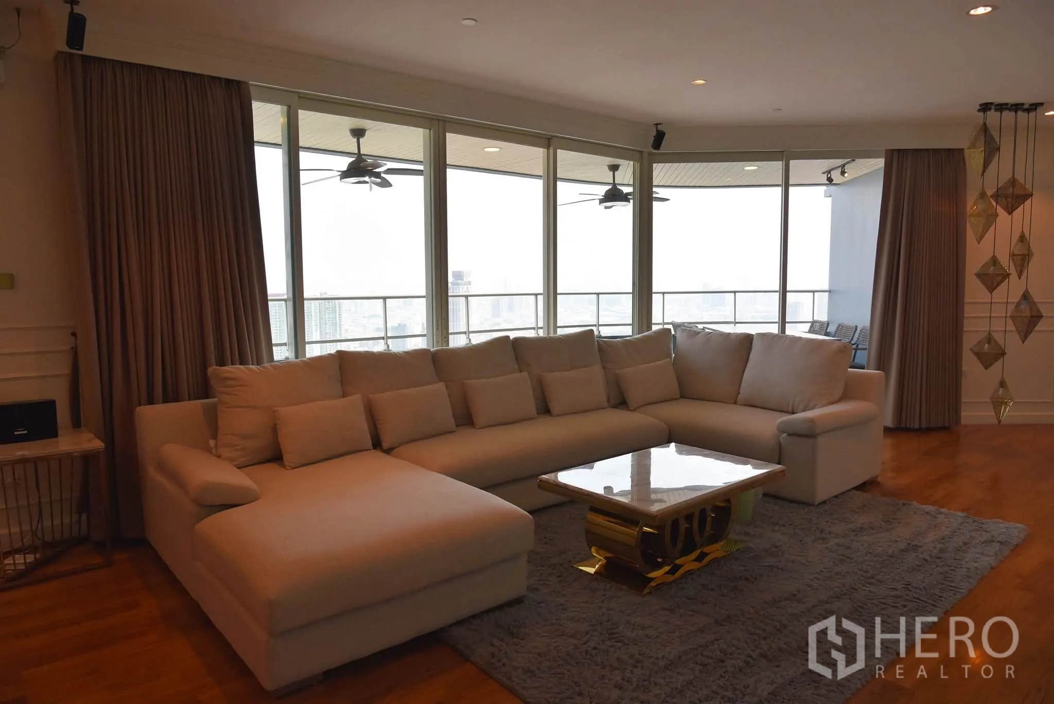 Condominium for sale in Khlong San, Bangkok - Spacious living room with L-shaped sofa, rug, and sliding doors opening to the balcony.