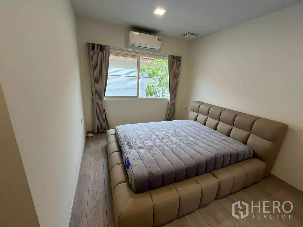 Detached House for rent in Bang Phli, Samut Prakan - Secondary bedroom with upholstered bed, air-conditioner, and wood flooring.