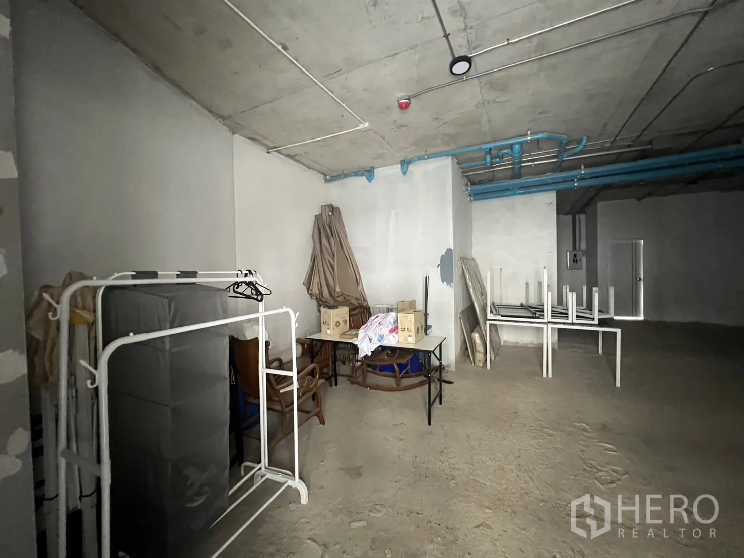 พื้นที่ขายปลีก ให้เช่า - มุมเก็บของในยูนิต มีชั้นวาง โต๊ะวางซ้อน และงานระบบที่มองเห็นได้